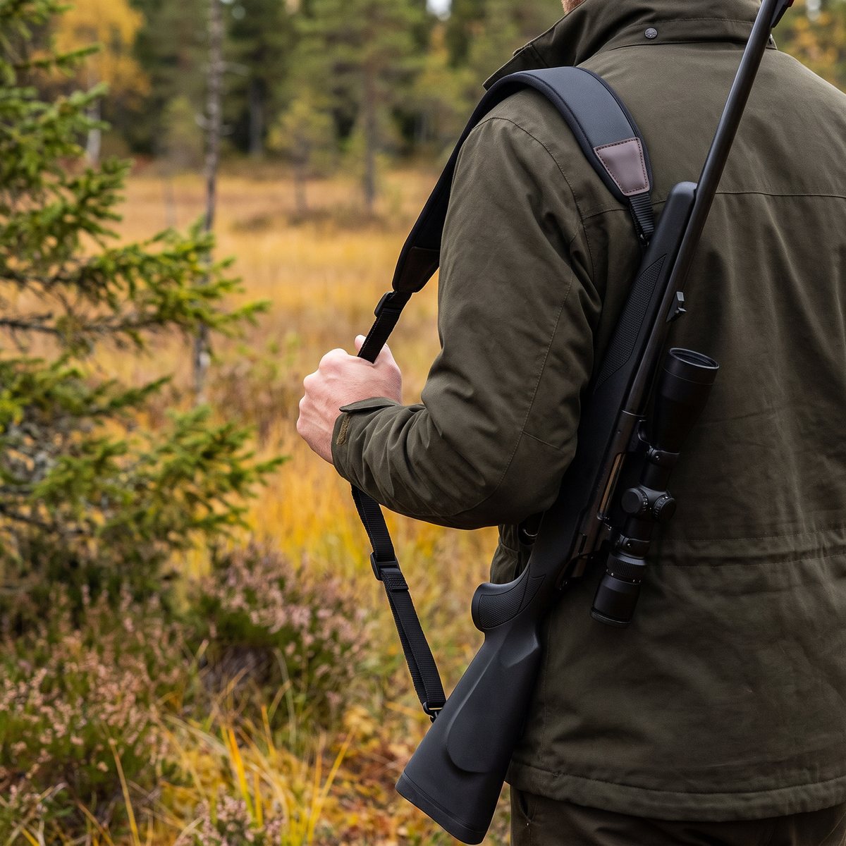 Browning Vapenrem Neoprene i svart neopren på axeln hos en jägare vid en myrkant med ljung och gran i svensk höstskog