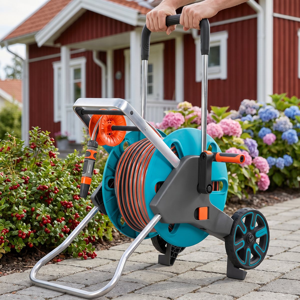 Slangvagnen Gardena AquaRoll M Easy rullas längs en stenlagd gång vid ett svenskt trähus