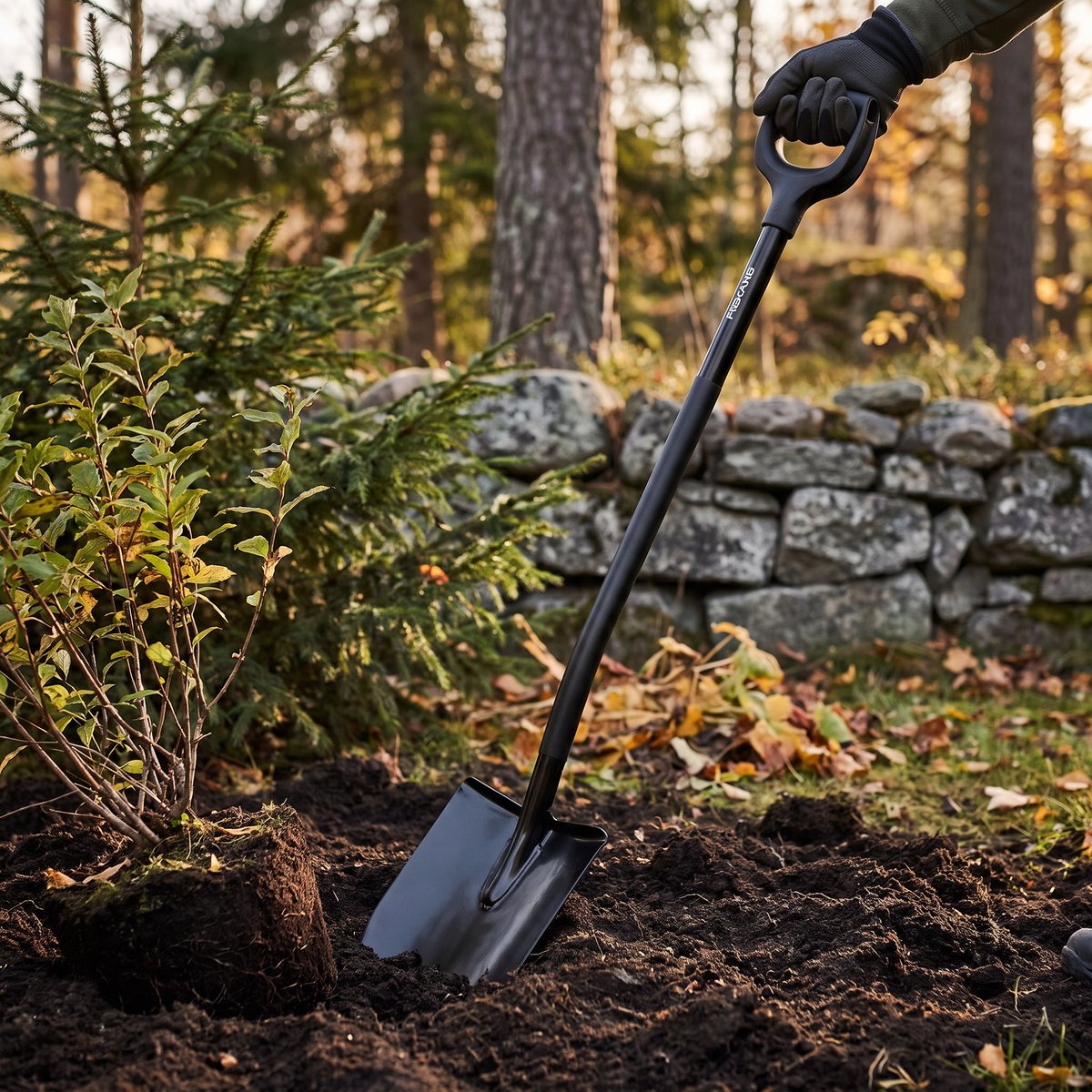 Svart Fiskars Ergonomic Pro-spade med spetsigt blad som gräver ett planteringshål i en svensk trädgård