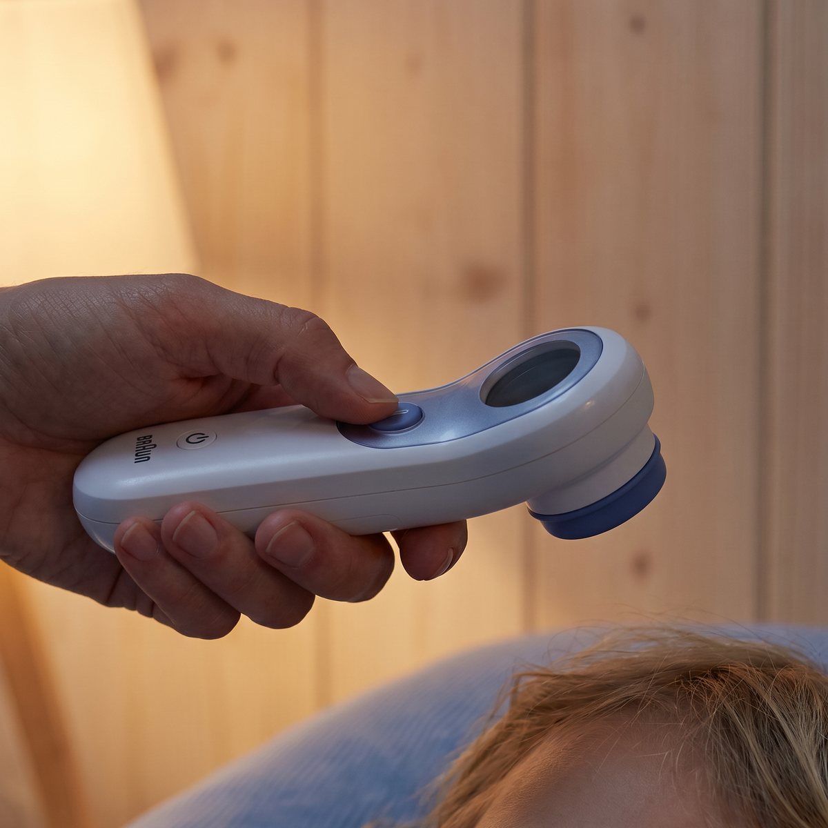Braun No Touch + Touch BNT300 hålls framför pannan på ett sovande barn i nattlampans sken i ett svenskt barnrum med panelväggar