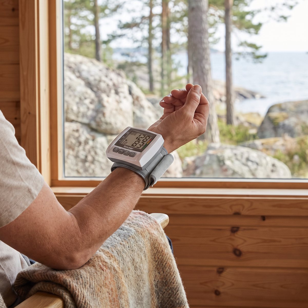 Beurer BC30 på handleden i en svensk sommarstuga med furupanel och utsikt över klippor och hav