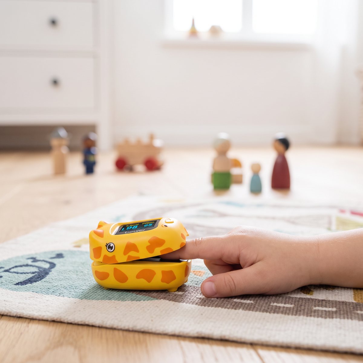 Beurer PO 13 Kids, giraffformad pulsoximeter, på ett barns finger på en lekmatta i ett svenskt barnrum