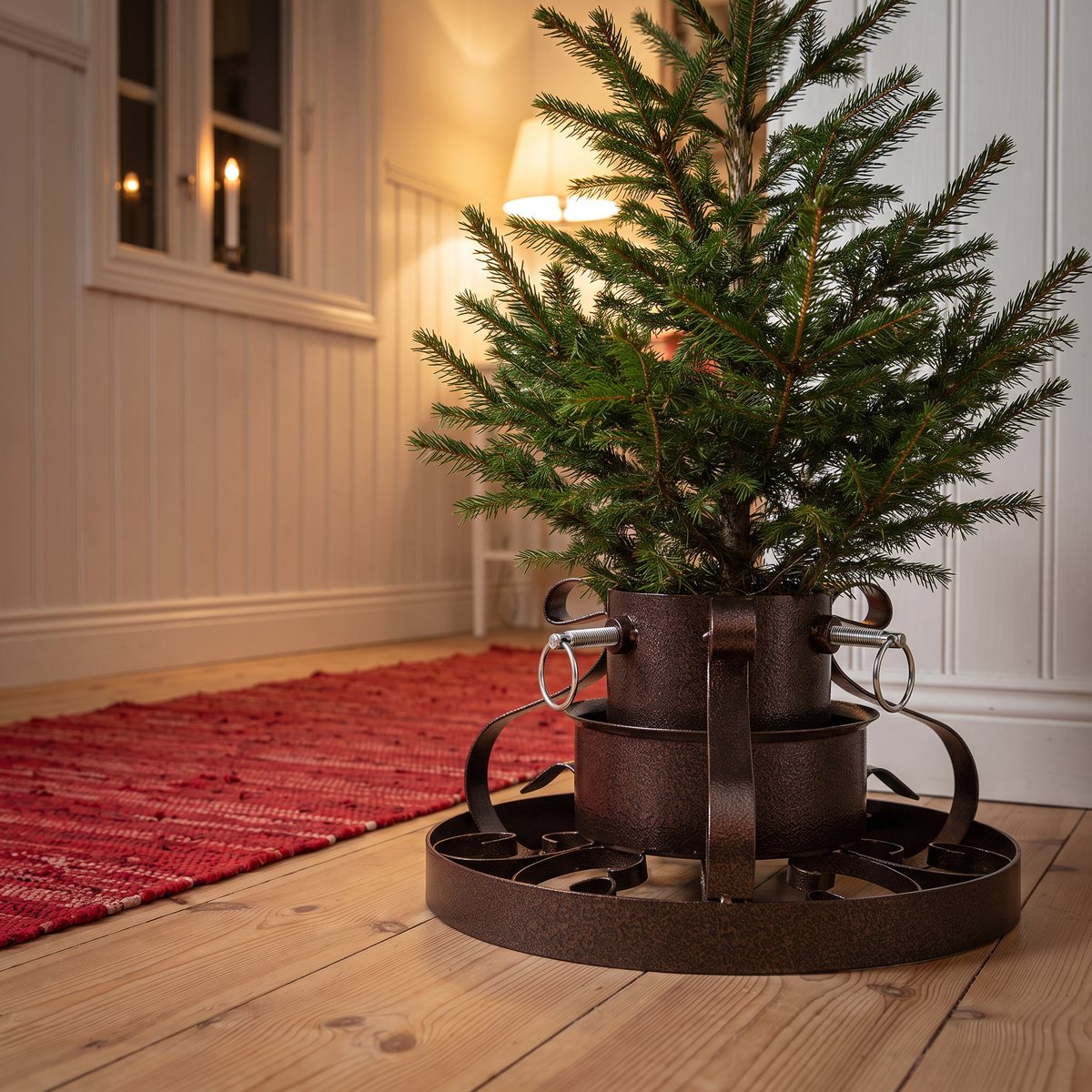 Liten gran i vidaXL:s julgransfot i antik koppar med svängda ornament på ett trägolv bredvid en röd trasmatta