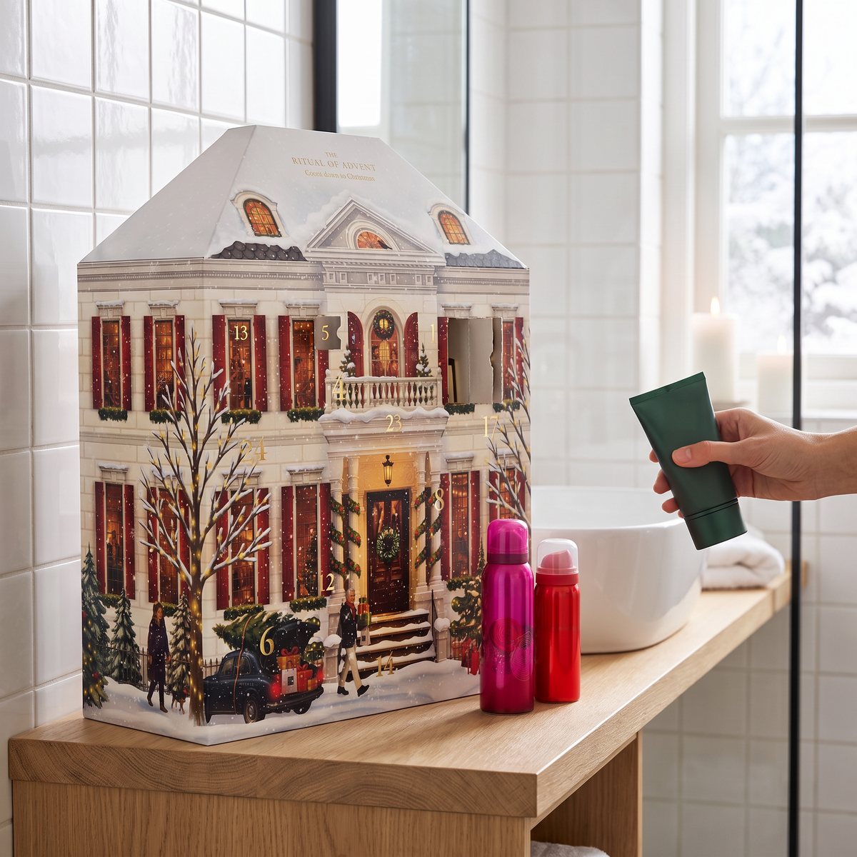 Rituals husformade adventskalender på en trähylla i ett vitkaklat badrum, med två små sprayflaskor och en hand som håller en tub.