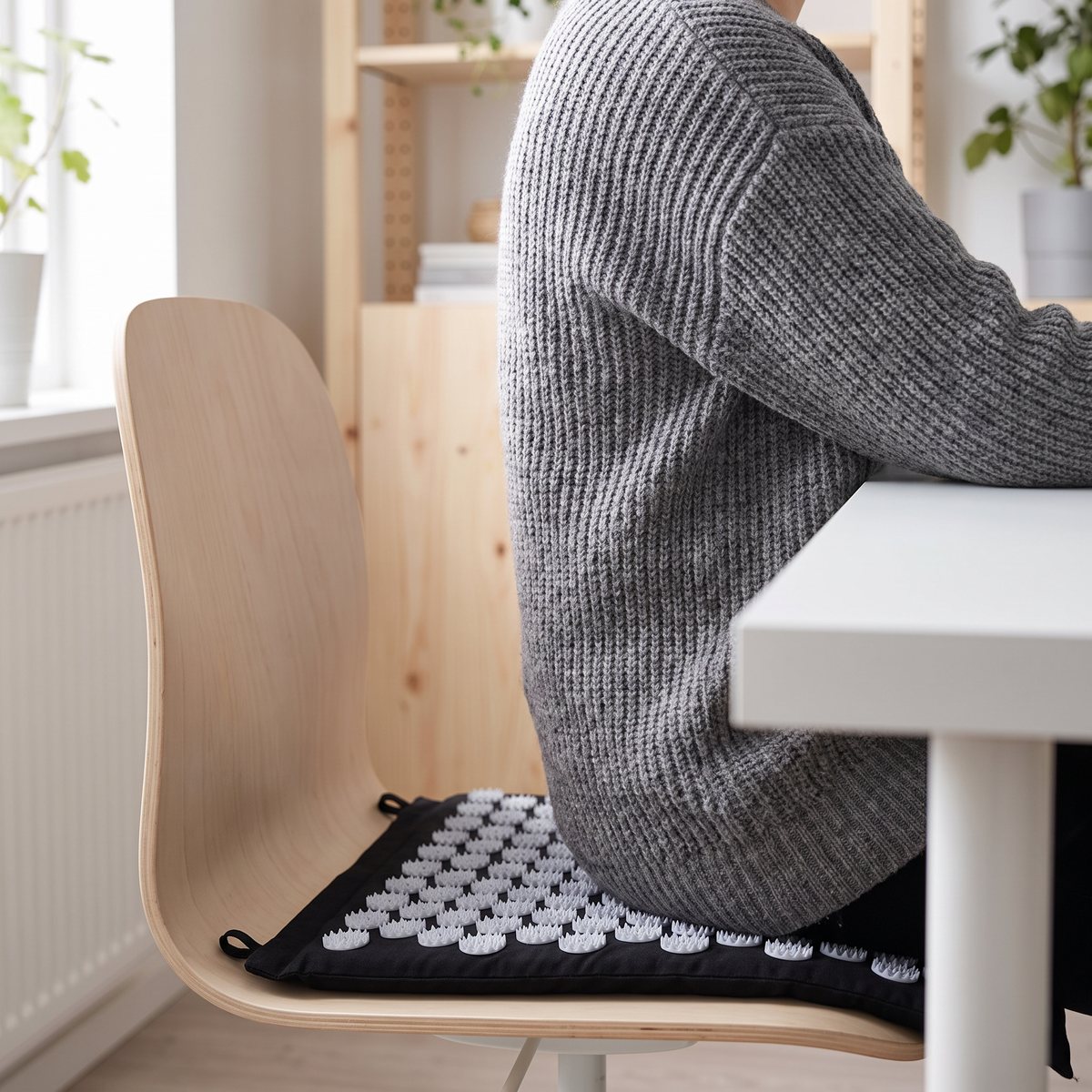 Svart spikmatta med ljusgrå piggskivor som används som sitt- och ryggstöd på en stol i ett svenskt hemmakontor