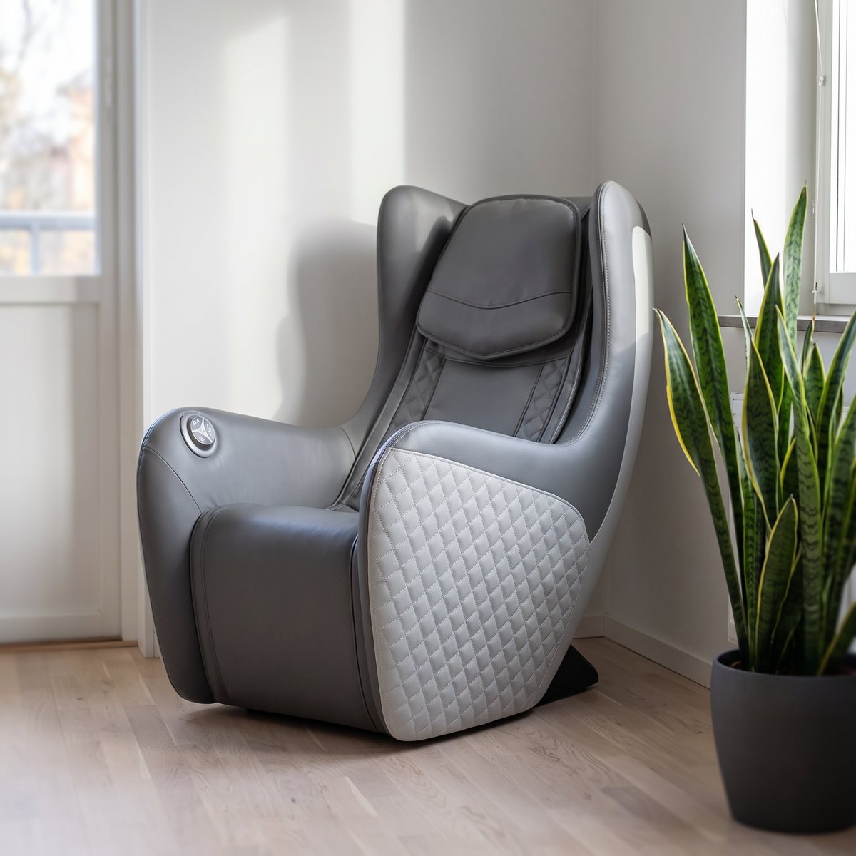 Kompakt grå massagefåtölj med rutsydd sidopanel i hörnet av en liten svensk lägenhet
