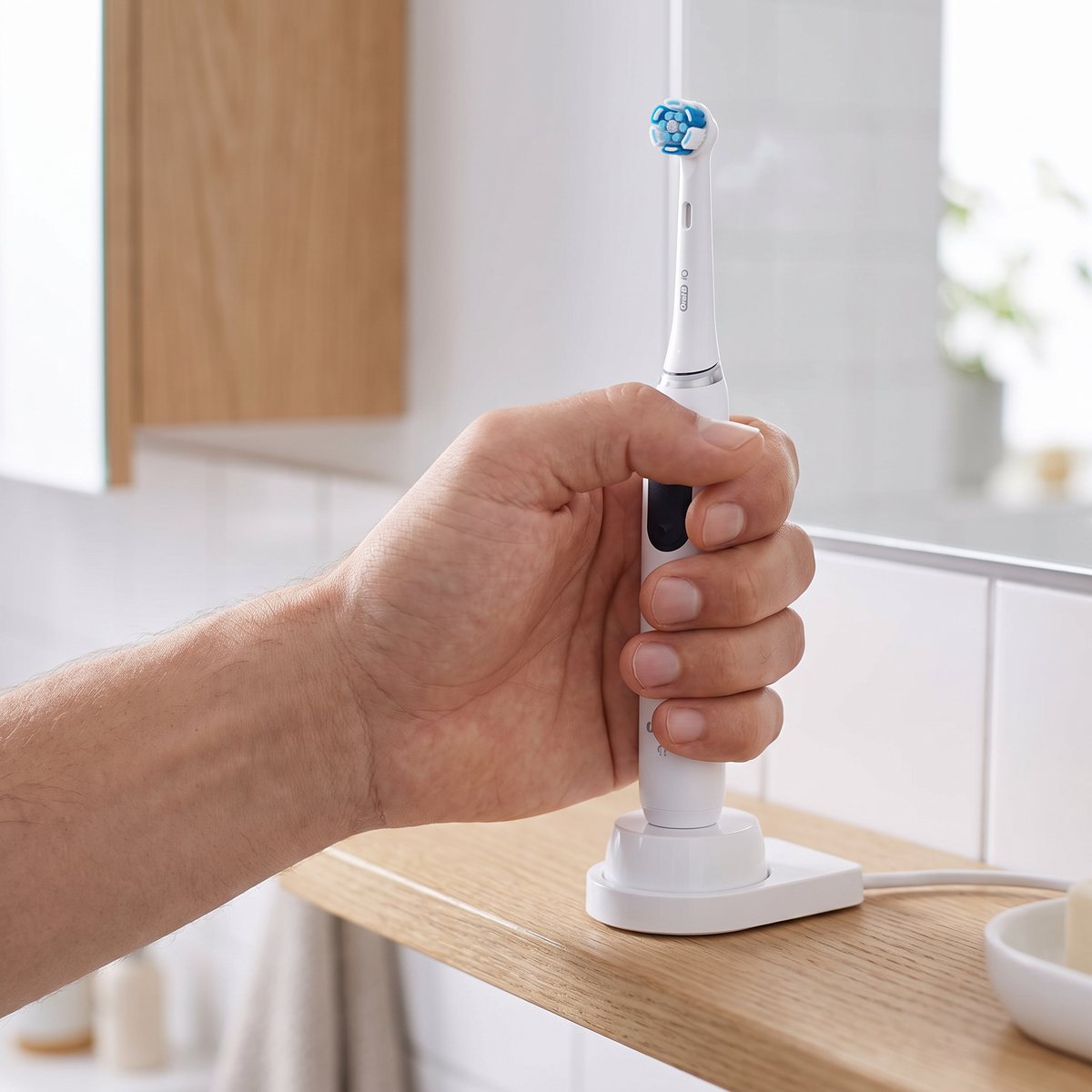 Oral-B iO Ultimate Clean-borsthuvud på ett skaft i laddställ på en ekhylla i ett svenskt badrum