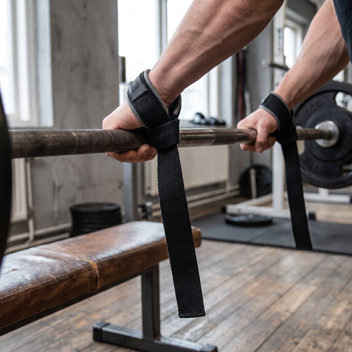 Svarta dragremmar i bomull runt en skivstång på ett svenskt gym