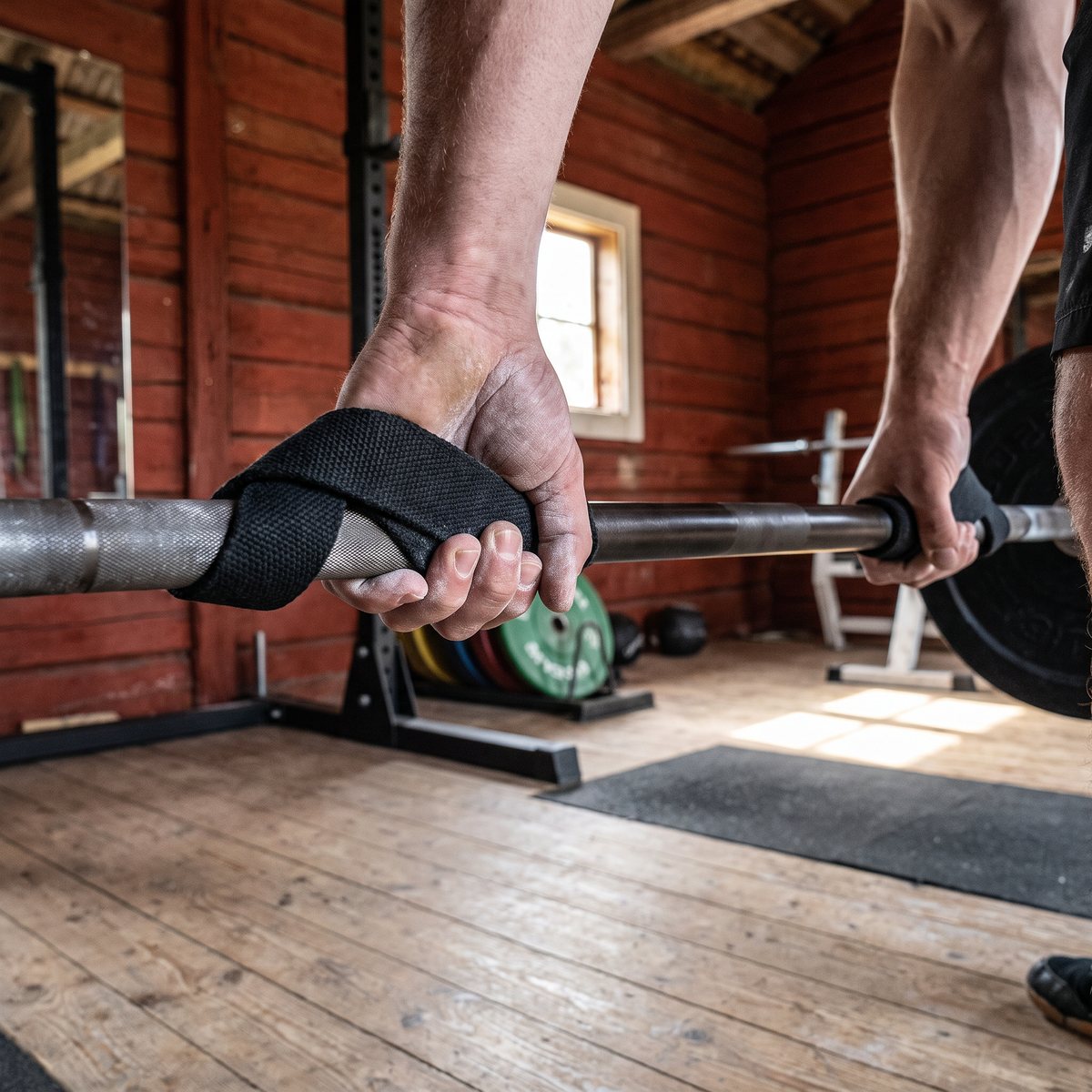 Svarta dragremmar i tjock väv runt en olympisk skivstång i ett svenskt gym