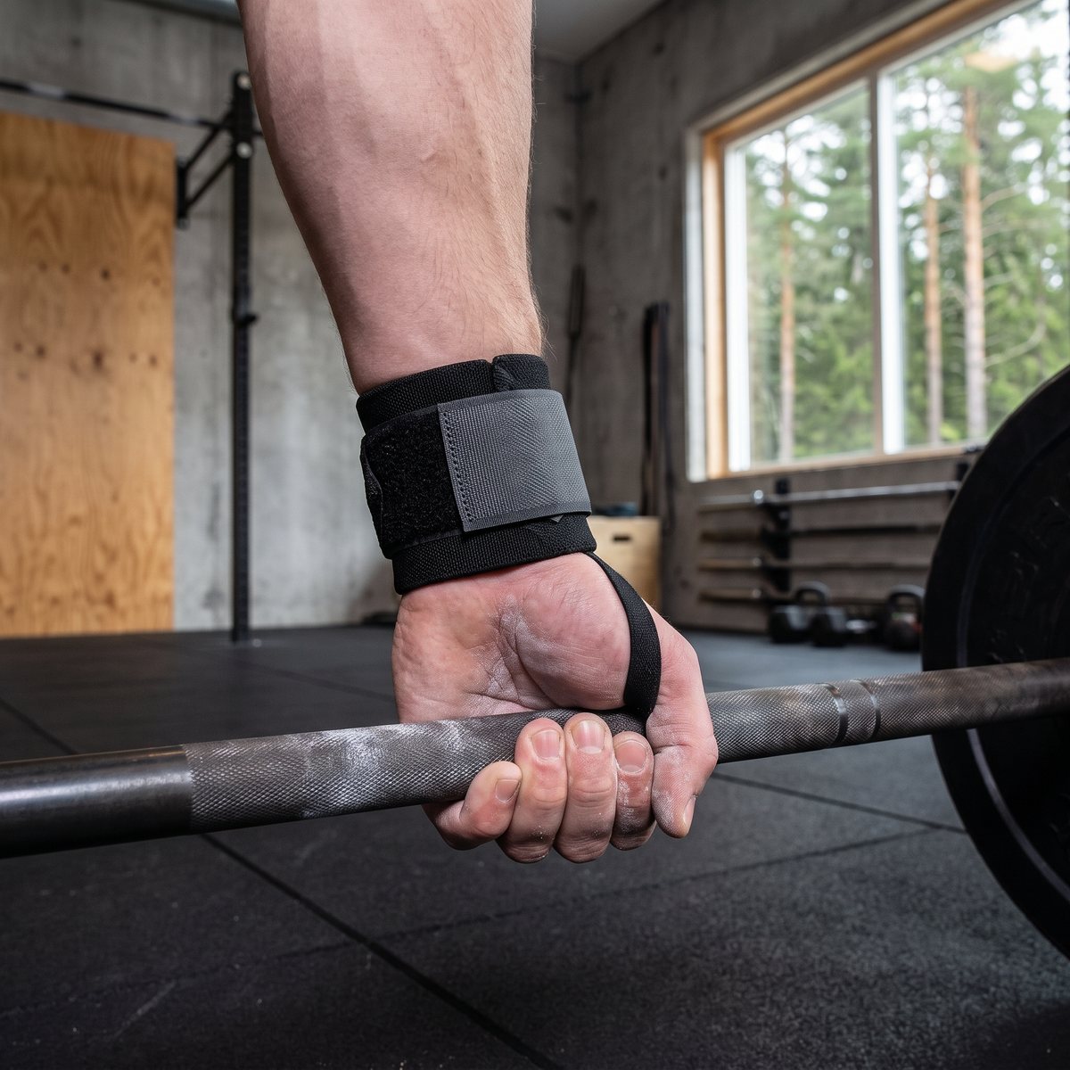 Svarta handledsstöd med grå yttre rem på en handled i ett svenskt gym under marklyft