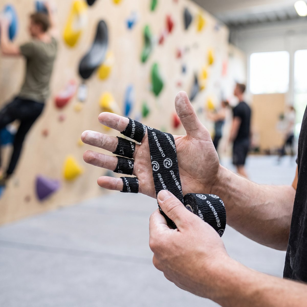 Svart självhäftande power wrap-tejp runt fingrarna på en klättrare i en svensk bouldering-hall