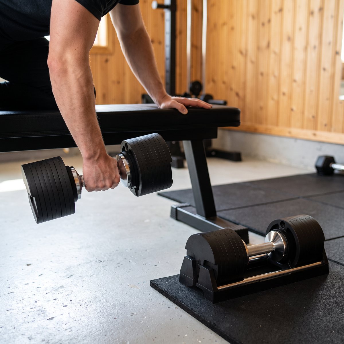 SNODE AD80 justerbar hantel i enarmsrodd vid en träningsbänk i ett svenskt garagegym med panelväggar och gummigolv