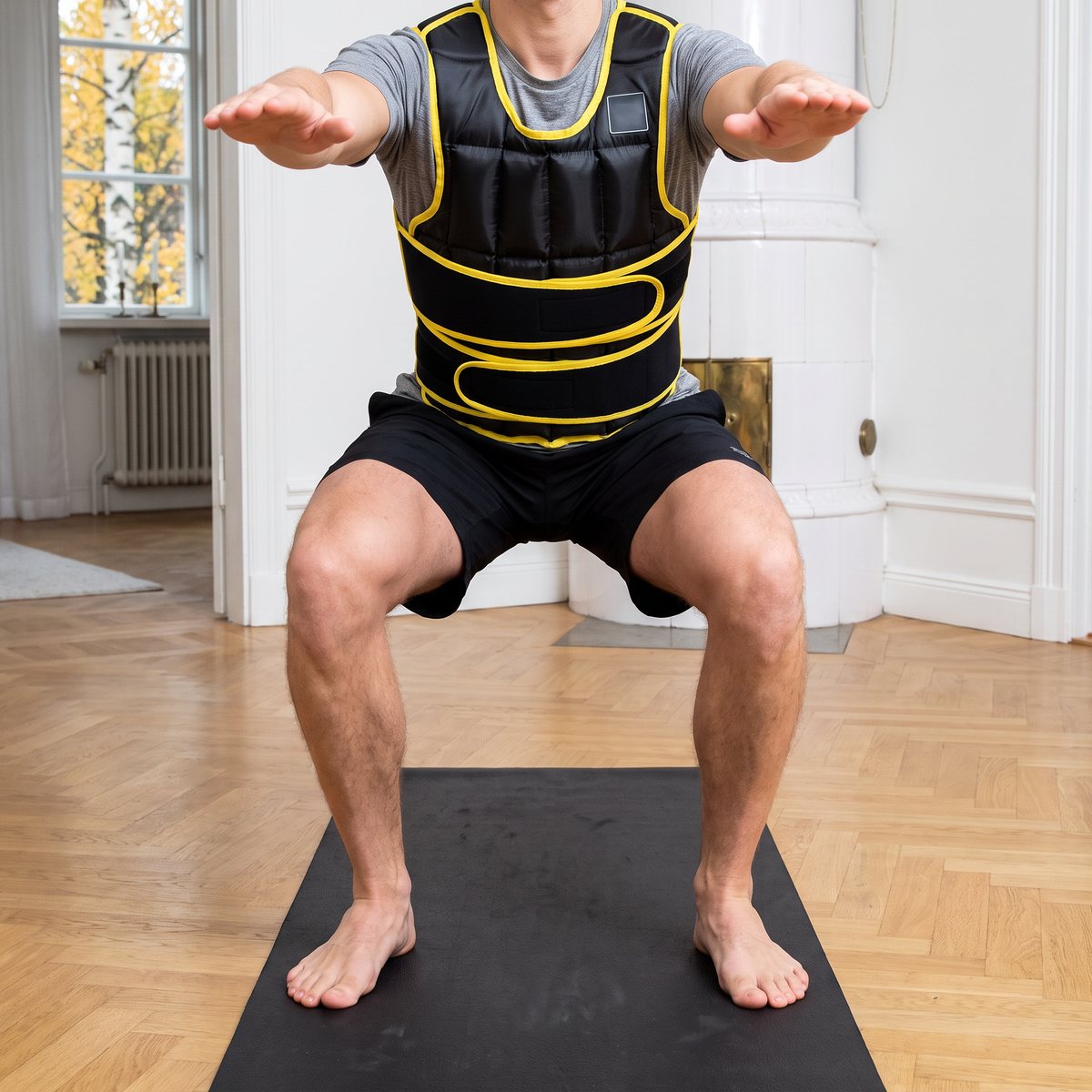 Person i Abilica WeightVest Power gör en knäböj på en yogamatta i ett ljust svenskt vardagsrum med kakelugn och fiskbensparkett