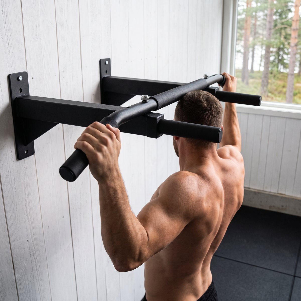 Väggmonterat chinsrack i ett svenskt garagegym, en man gör en chins