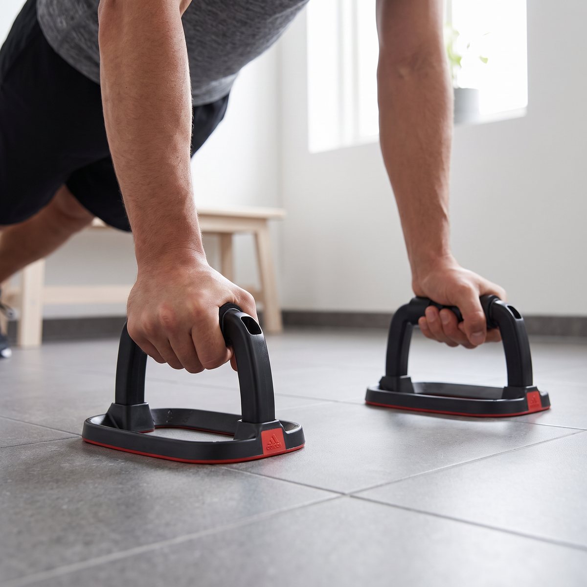 Armhävningar med Adidas Performance Push Up Bars på ett grått klinkergolv i en svensk lägenhet