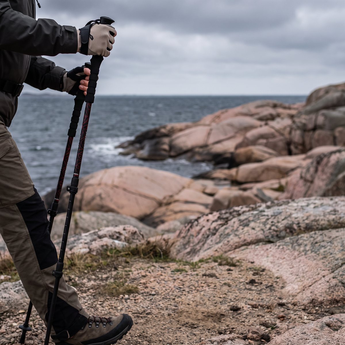 Svarta teleskopiska stavar används på en kuststig på svenska västkusten med rosa granithällar