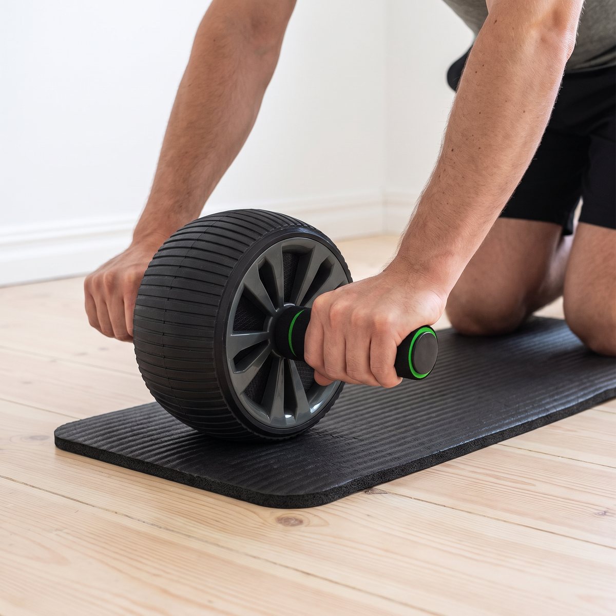 Tunturi Pro Deluxe Ab Wheel används från knästående på knämattan på ett ljust trägolv i ett svenskt hem