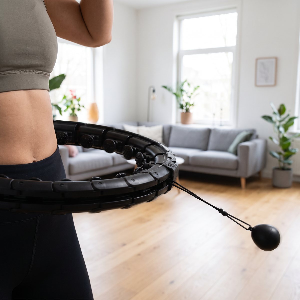 Svart justerbar massagehulahoppring med vikt på lina, använd runt midjan i ett svenskt vardagsrum