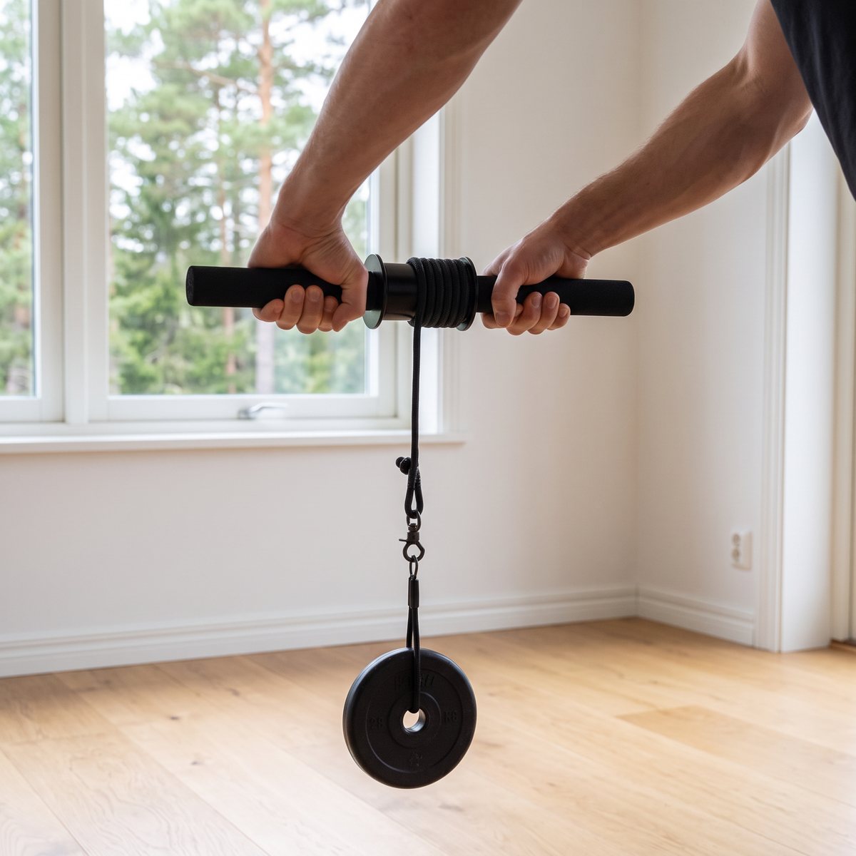 Wrist roller med svart skumstång och rep där en viktskiva hänger, tränad i ett svenskt hemmagym.