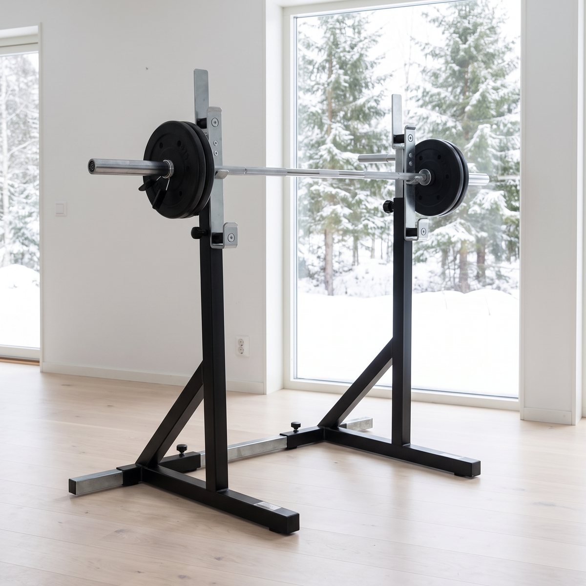 Squatställning med silverfärgade justerbara toppar i ett ljust svenskt hemmagym med snöig granskog utanför
