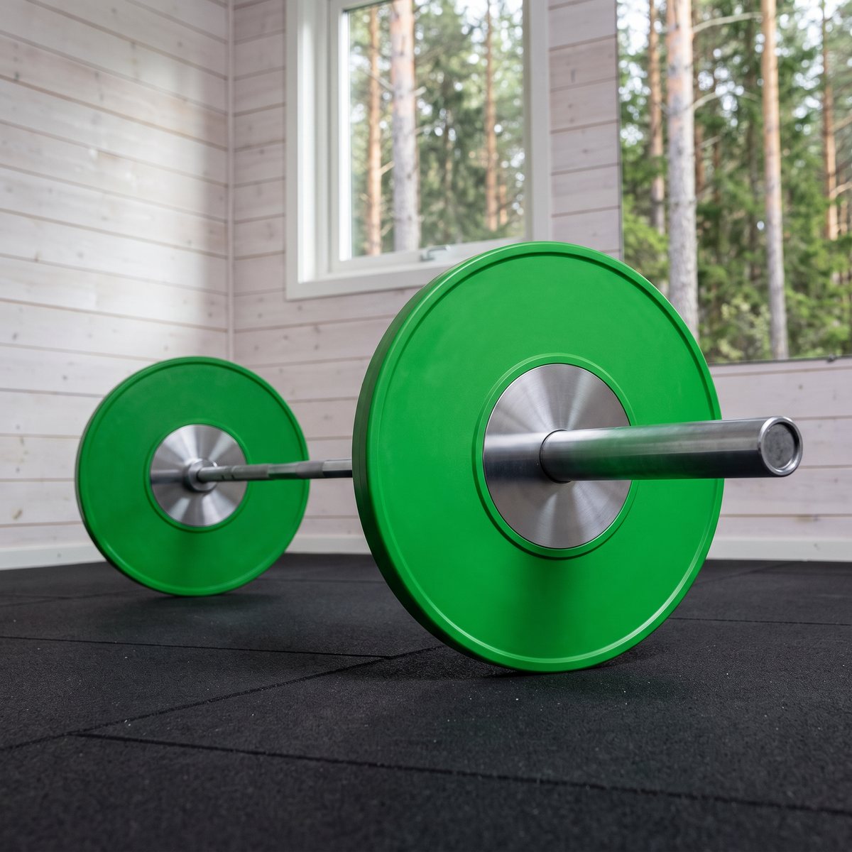 Grön tävlingsbumperskiva på skivstång i ett svenskt garagegym