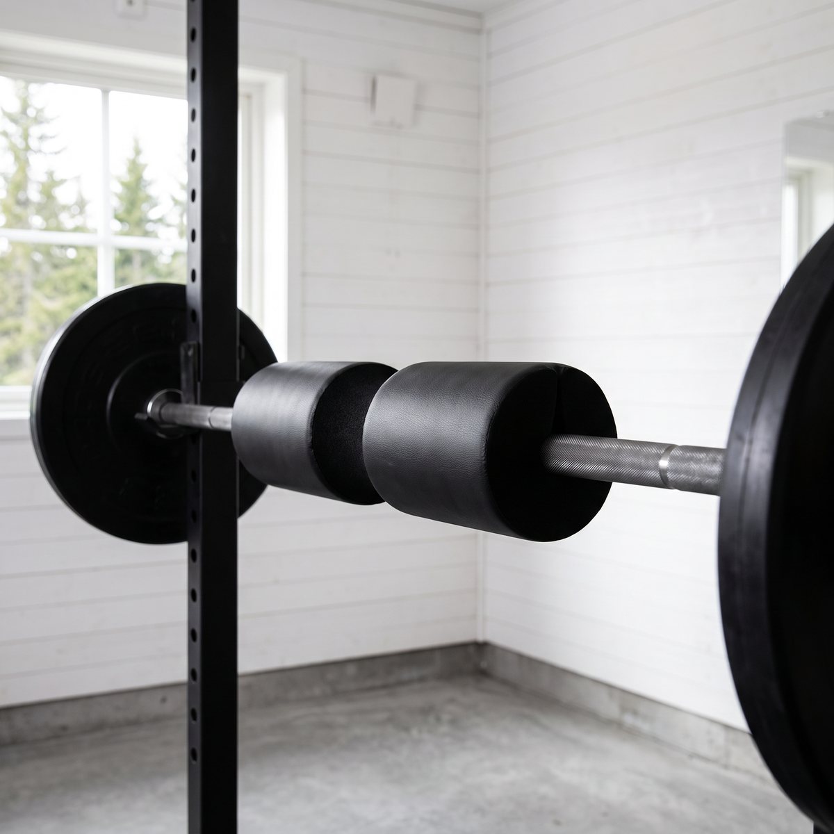 Abilica Squatpad på en skivstång med viktskivor i ett ljust svenskt garagegym med vita träväggar
