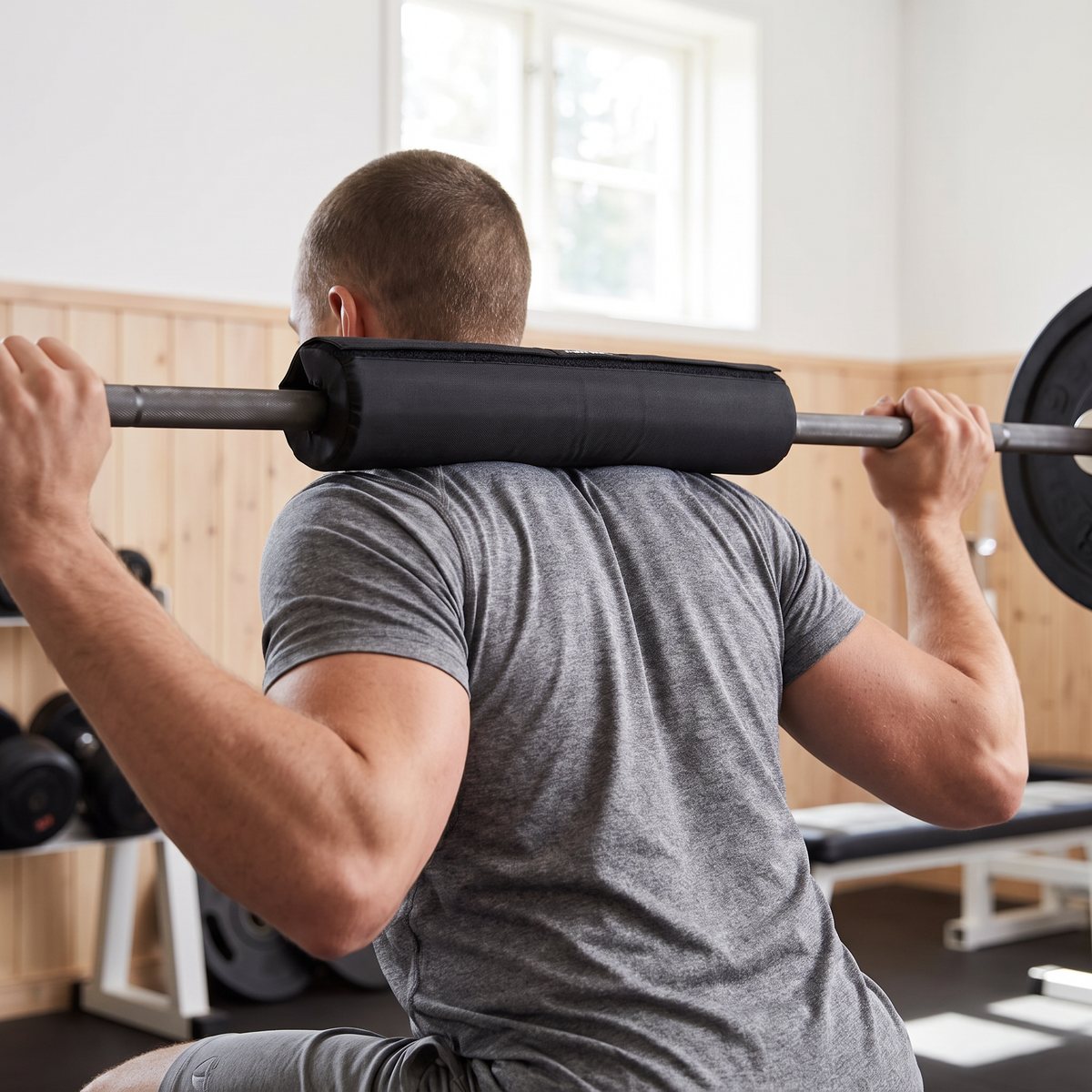 Master Fitness Barbell Padding på skivstången i ryggen vid en knäböj i ett svenskt gym med träpanel