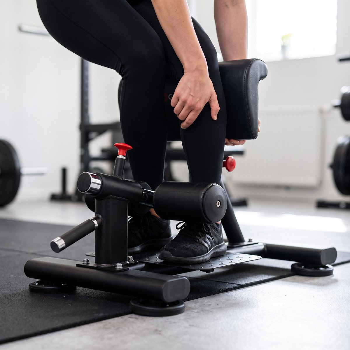 Gymstick Sissy Squat Pro med röd låsstift och sugkoppsfötter i ett svenskt källargym