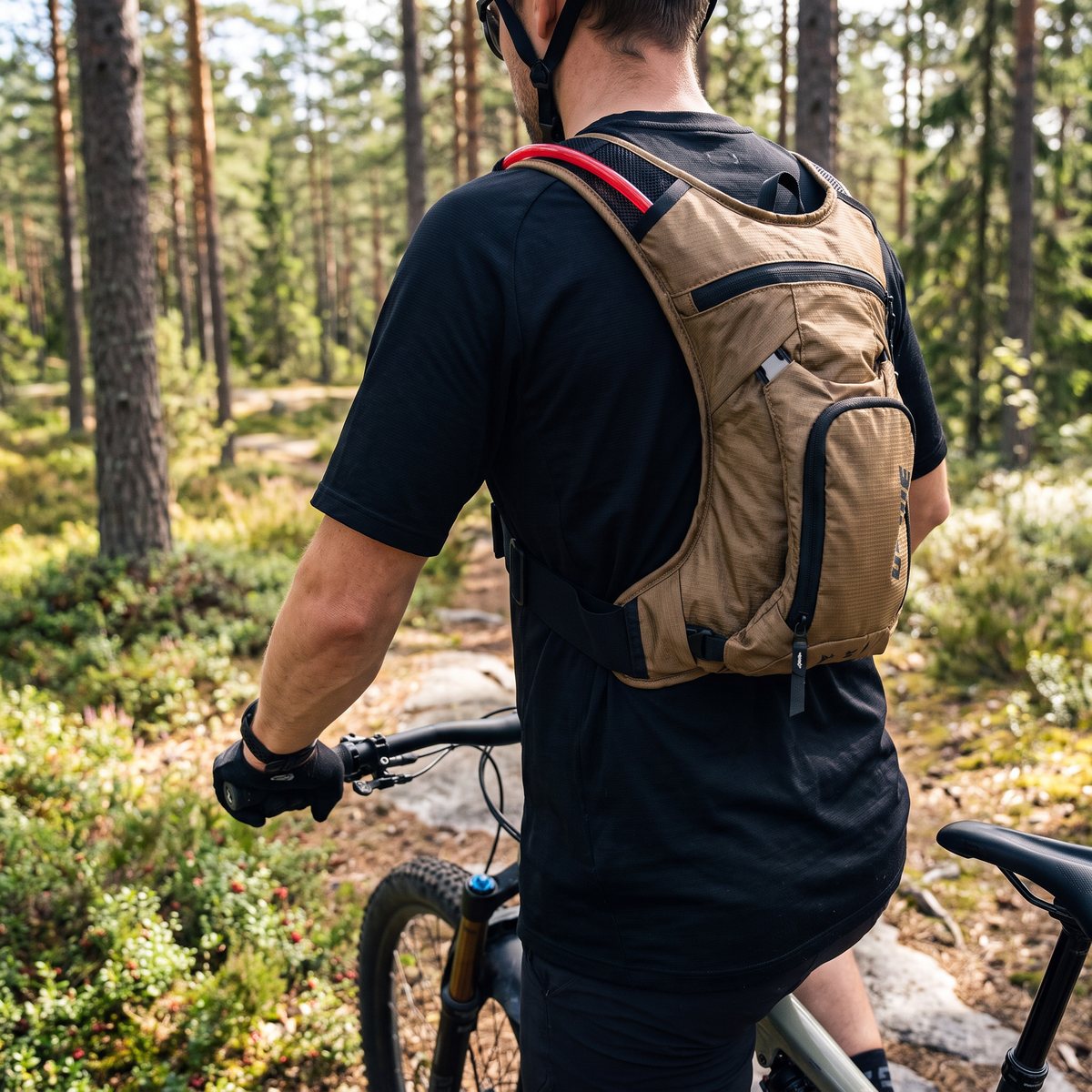 Brun USWE Mtb Hydro 3 cykelsäck på en mountainbikecyklist på en stig i svensk tallskog