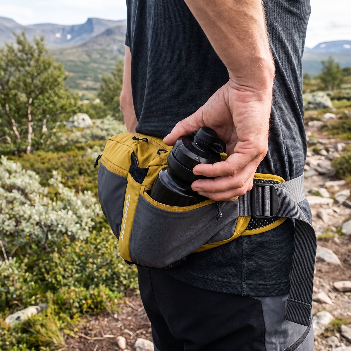 Vandrare på en fjällstig i Jämtland med CamelBak Podium Flow 4 runt midjan och flaskan i handen
