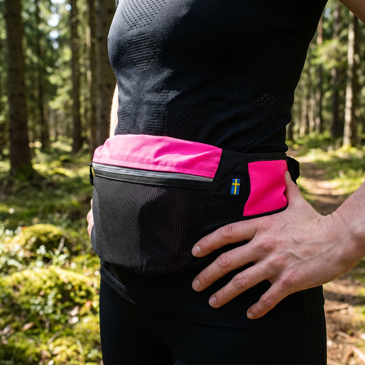 Löpare i svensk granskog på våren med Coxa WR1 Race i rosa och svart runt midjan