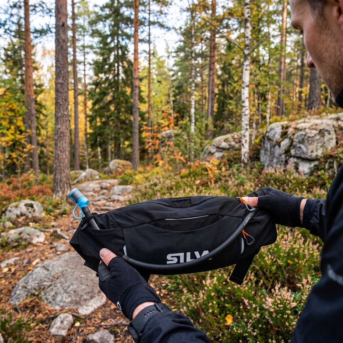 Löpare i svensk tallskog på hösten med Silva Race Belt 4 med dryckesslang i händerna