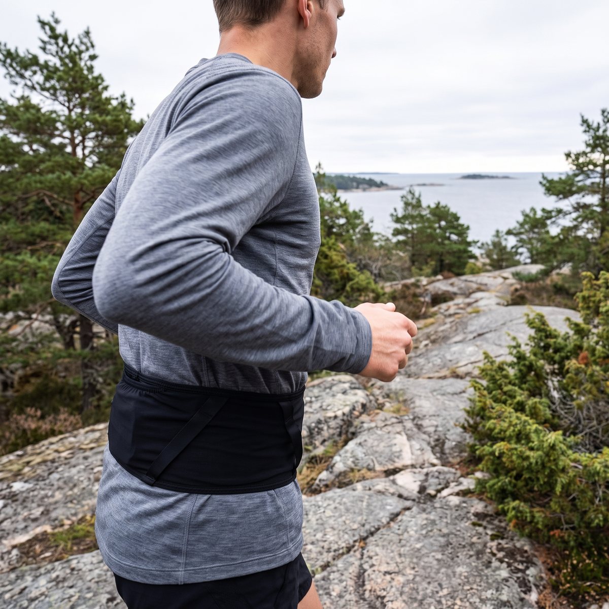 Löpare på berghäll vid svensk skärgårdskust med svart Salomon High Pulse Belt runt midjan