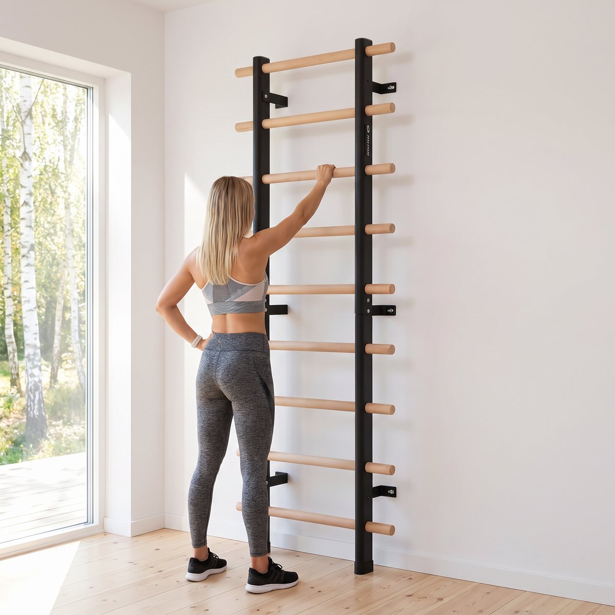 Abilica Premium WallBar ribbstol på vit vägg i ett ljust svenskt hemmagym, en kvinna står bredvid med handen på en spjäla