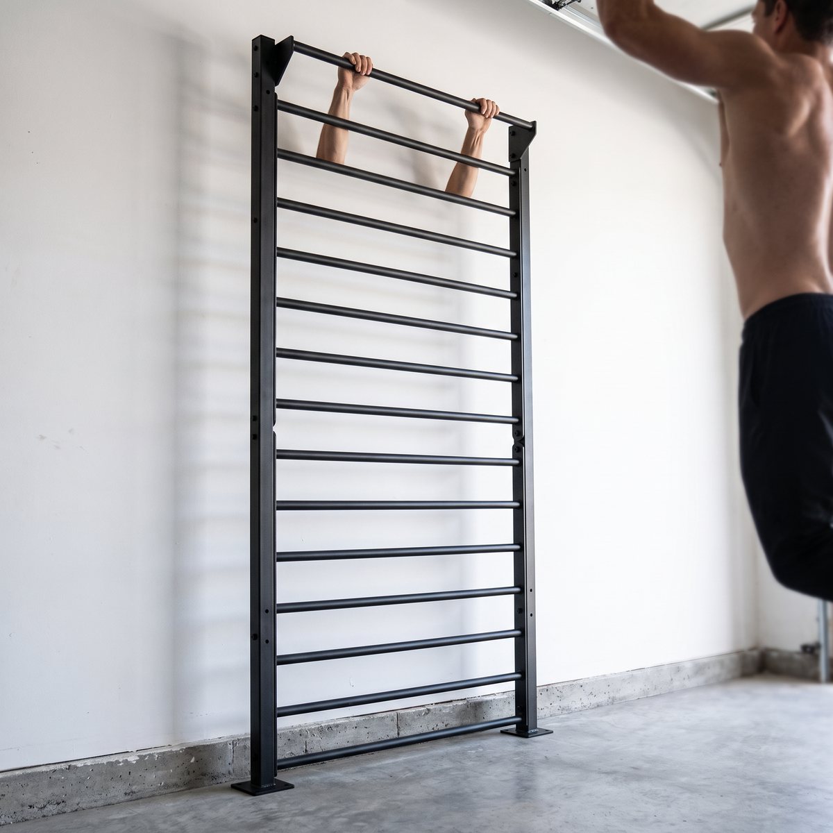 Recoil Ribbstol Kommersiell i svart stål i ett svenskt garagegym, en person hänger i den övre stången