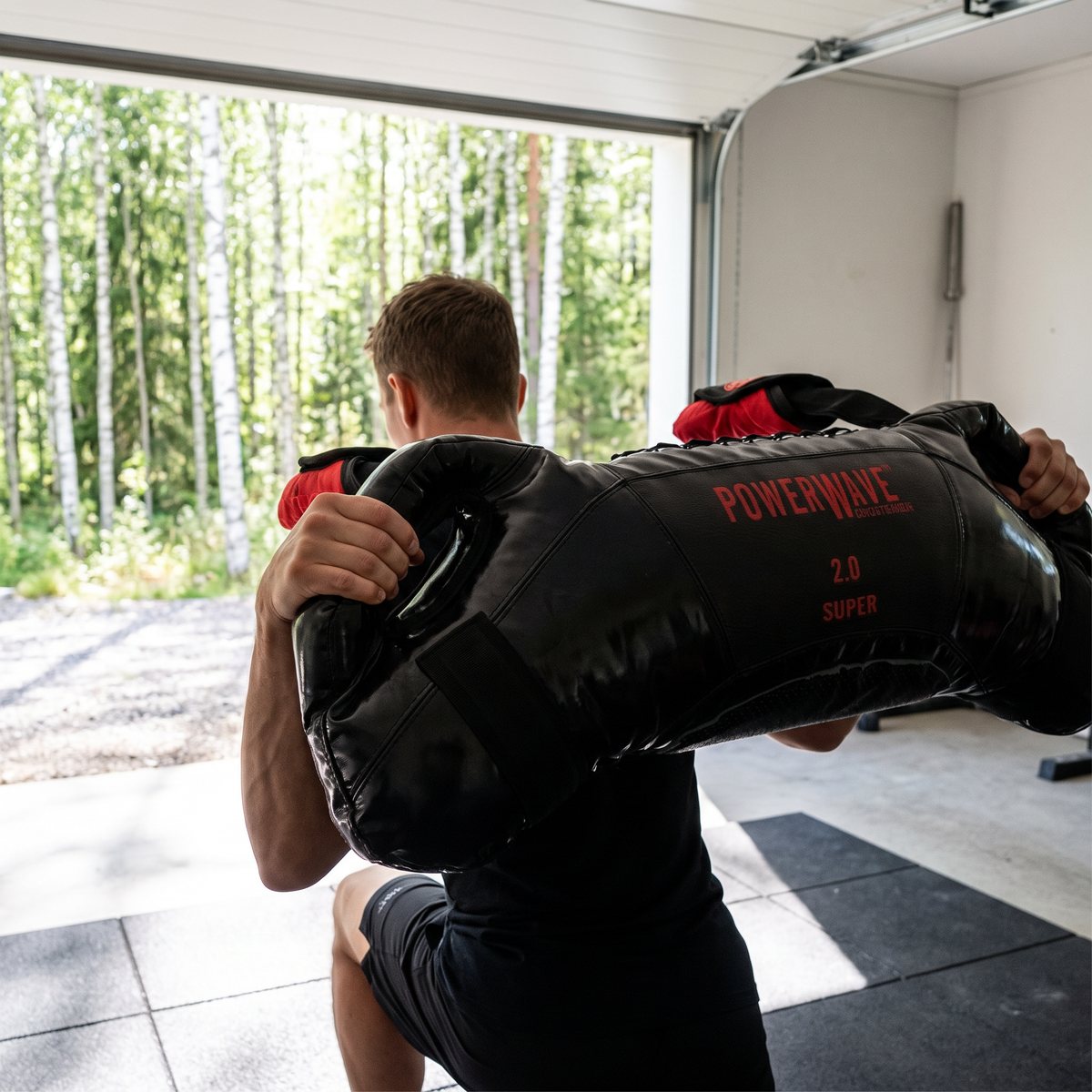 Svart Powerwave Classic Super bärs över axlarna vid utfallssteg i ett svenskt garagegym