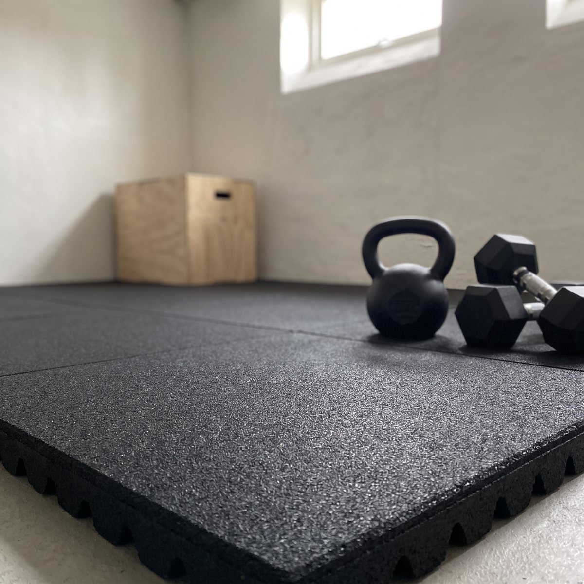 Svart gummigolv från Gymkompaniet med kettlebell och hantlar i ett svenskt källargym