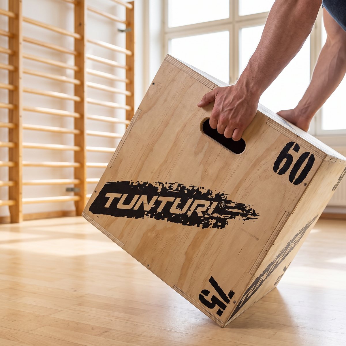 Tunturi Plyo Box Wood, plyobox i trä, hållen i handtagshålet i en svensk gymnastiksal