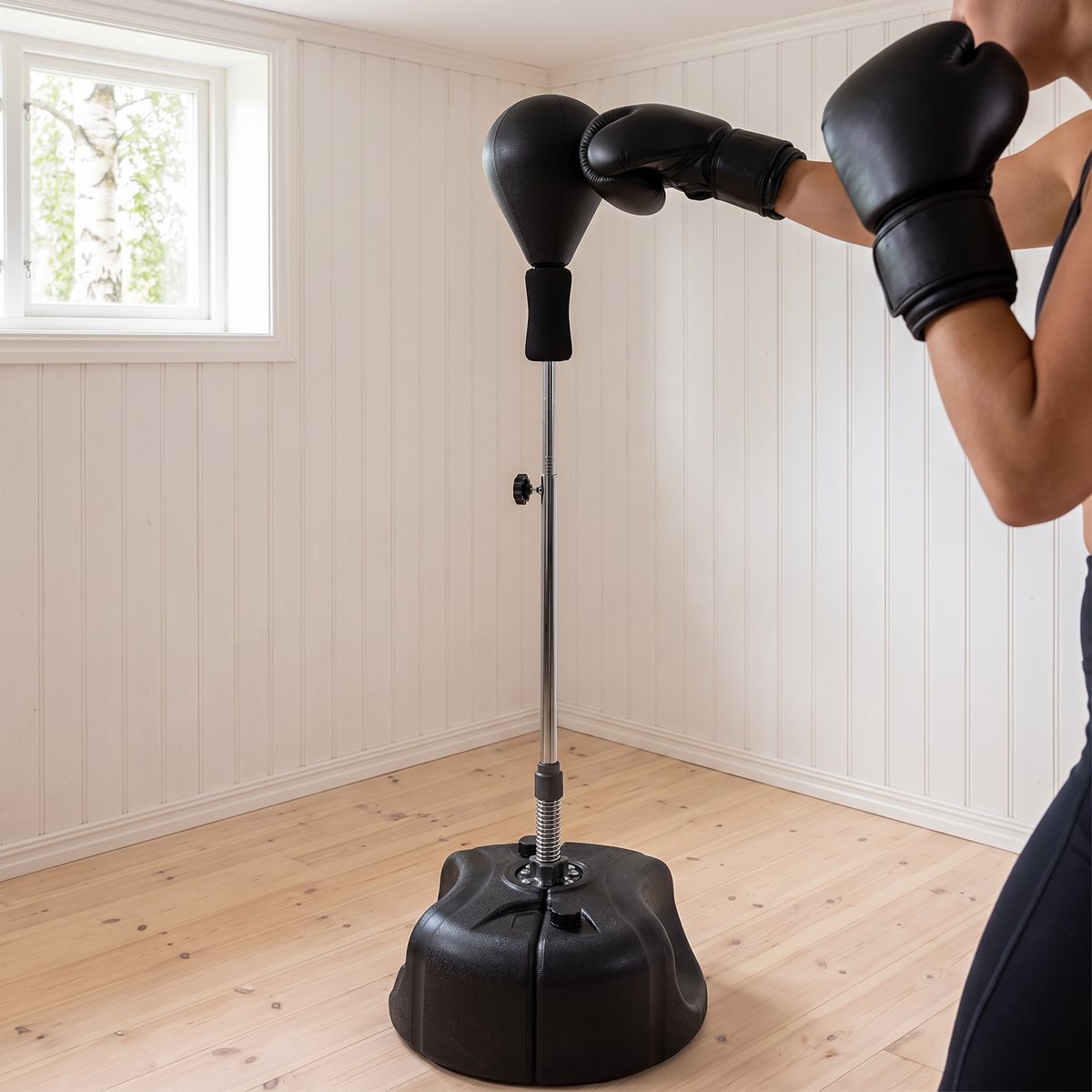 Boxare i svart handskar slår på Tunturi Speedball On Stand i ett ljust svenskt hemmagym med furugolv