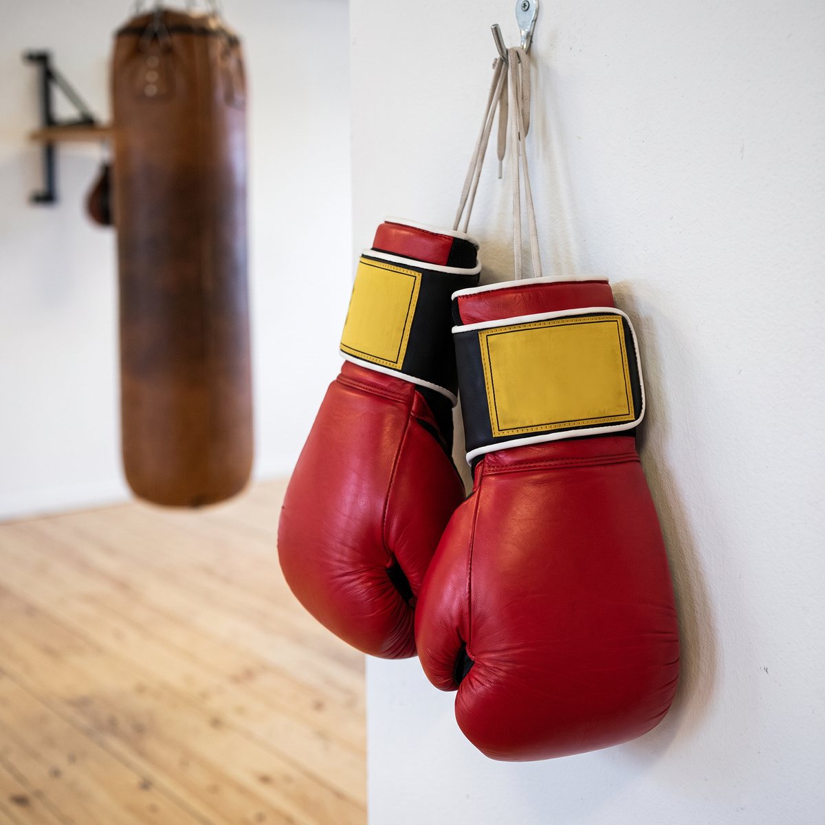 Röda Everlast 1910 Classic-boxningshandskar i läder hängande på en vit vägg i en svensk boxningslokal
