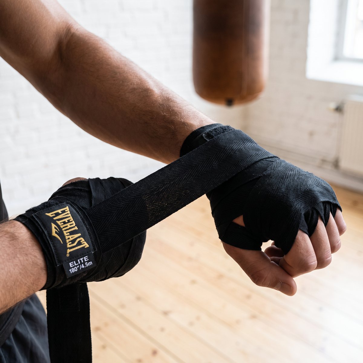 Boxare lindar en svart handlinda runt handled och knogar i ett ljust svenskt boxningsgym