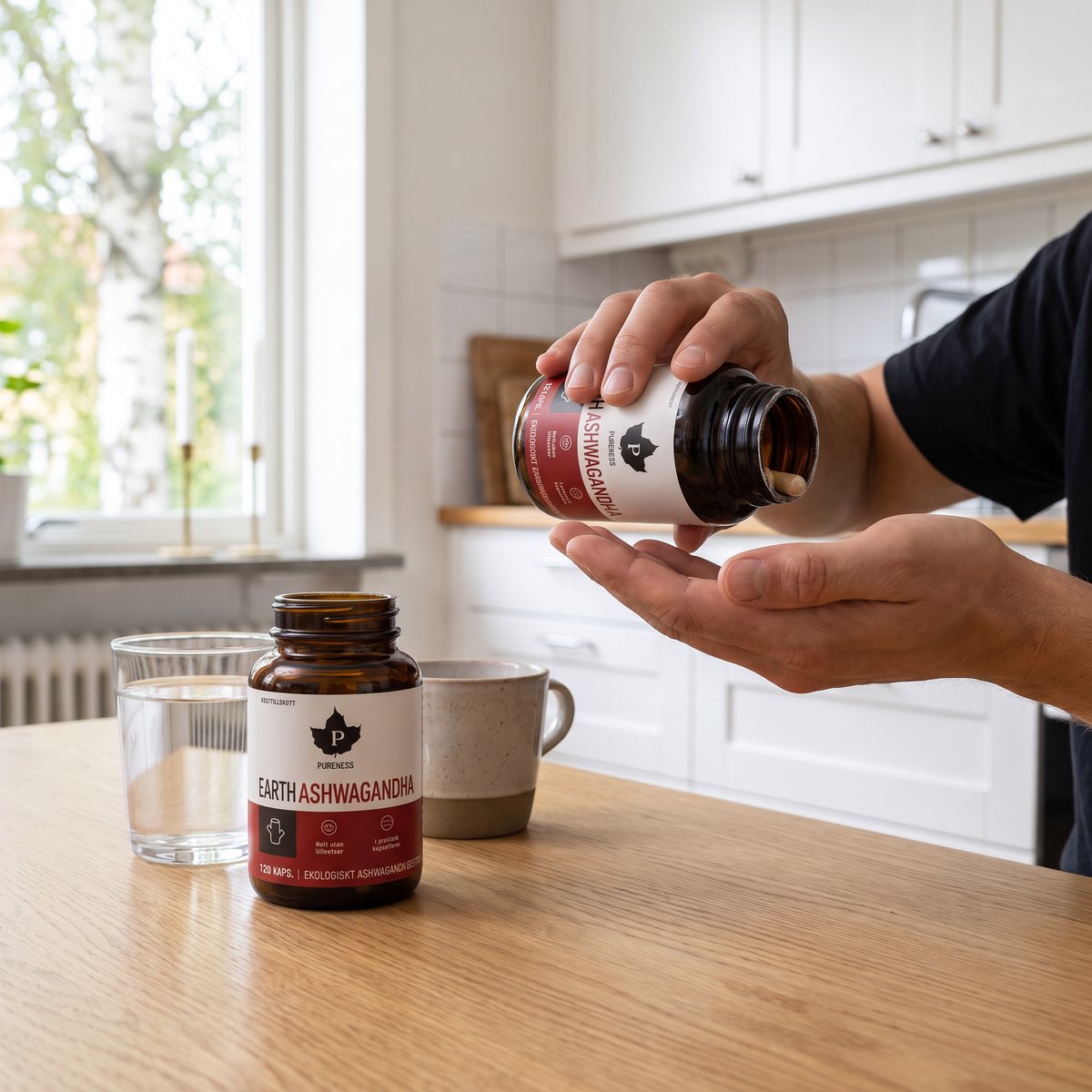 Burk med Pureness Earth Ashwagandha på ett ljust ekbord i ett svenskt kök, med en kapsel som hälls ut i handen och ett glas vatten bredvid