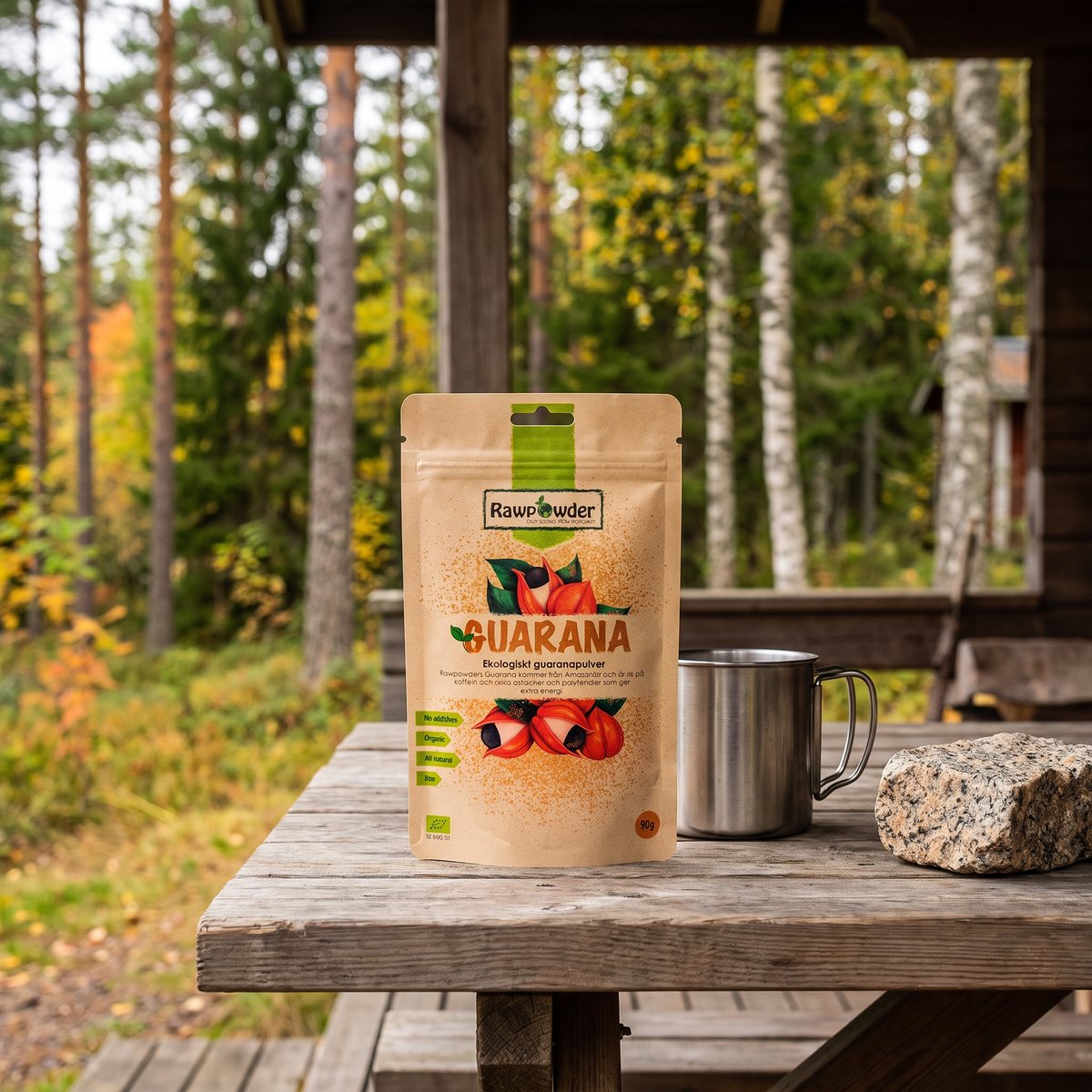 Kraftbrun påse med Rawpowder guaranapulver på ett träbord vid en stuga i svensk skog