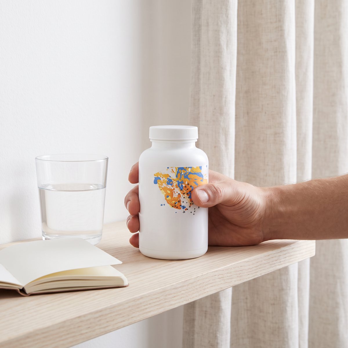 Vit tillskottsburk på en hylla i ett ljust svenskt hem bredvid ett glas vatten