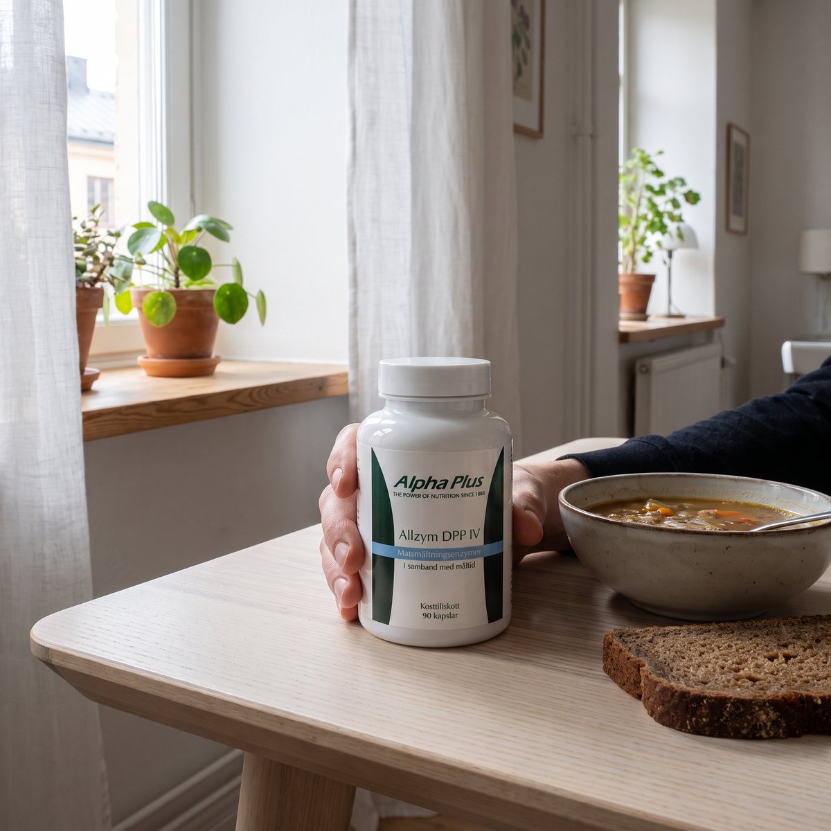 Alpha Plus Allzym DPP IV i handen vid ett bord med soppa och rågbröd i en svensk lägenhet