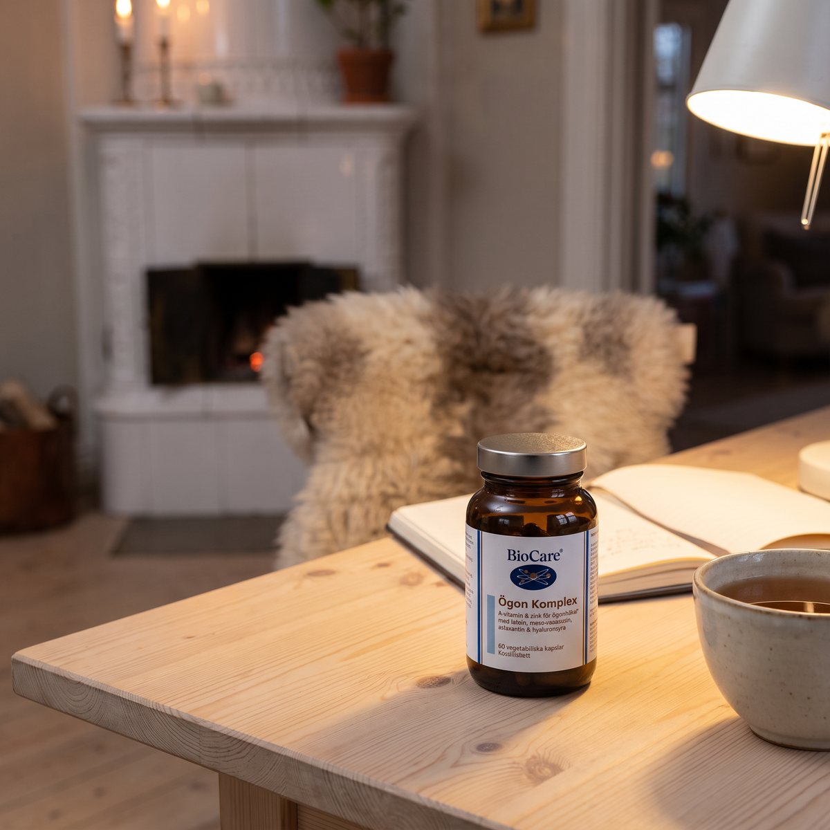 Burk BioCare Ögon Komplex på ett skrivbord i furu i ett mysigt svenskt vardagsrum med kakelugn och fårskinn