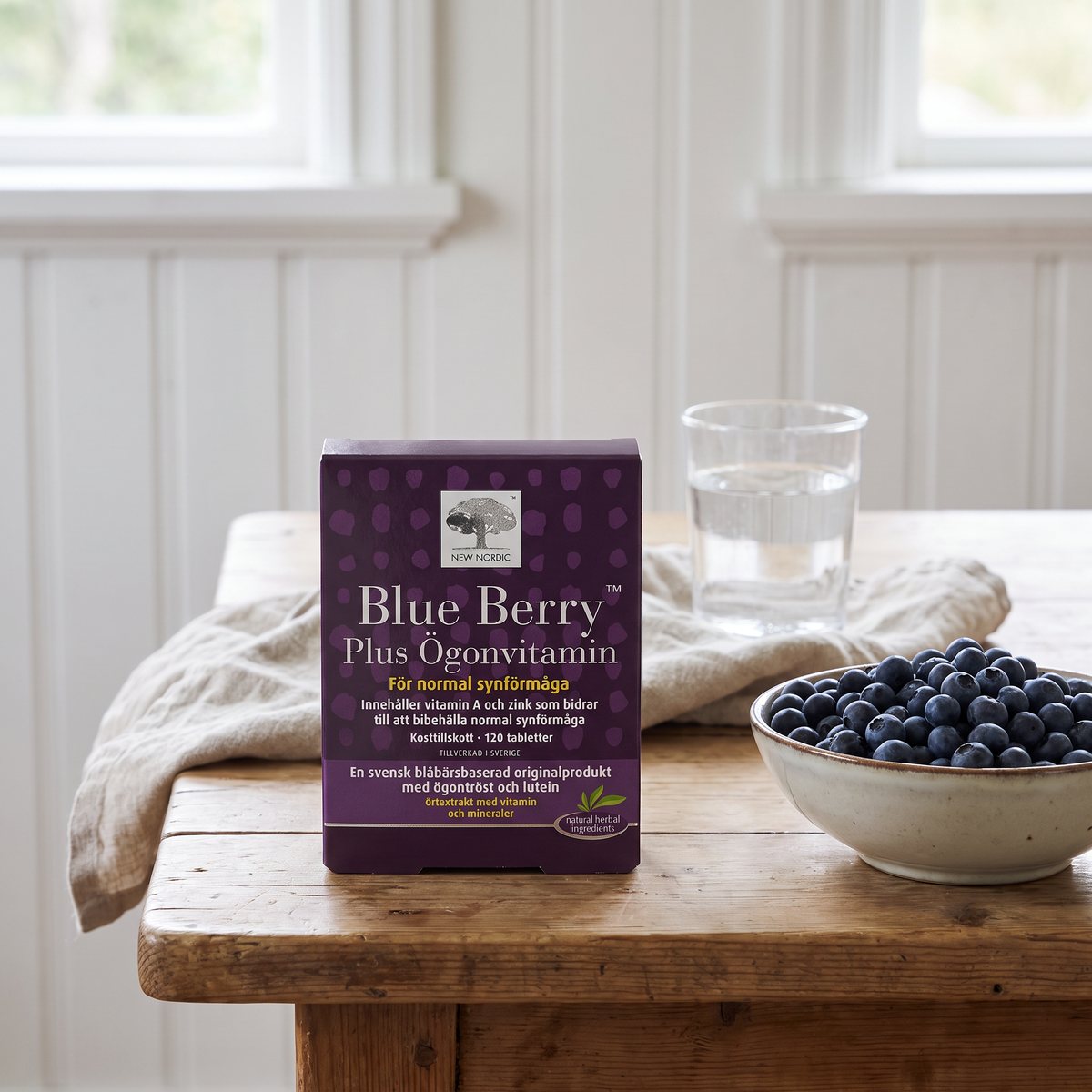 Ask New Nordic Blue Berry Plus bredvid blåbär och vattenglas på ett svenskt köksbord