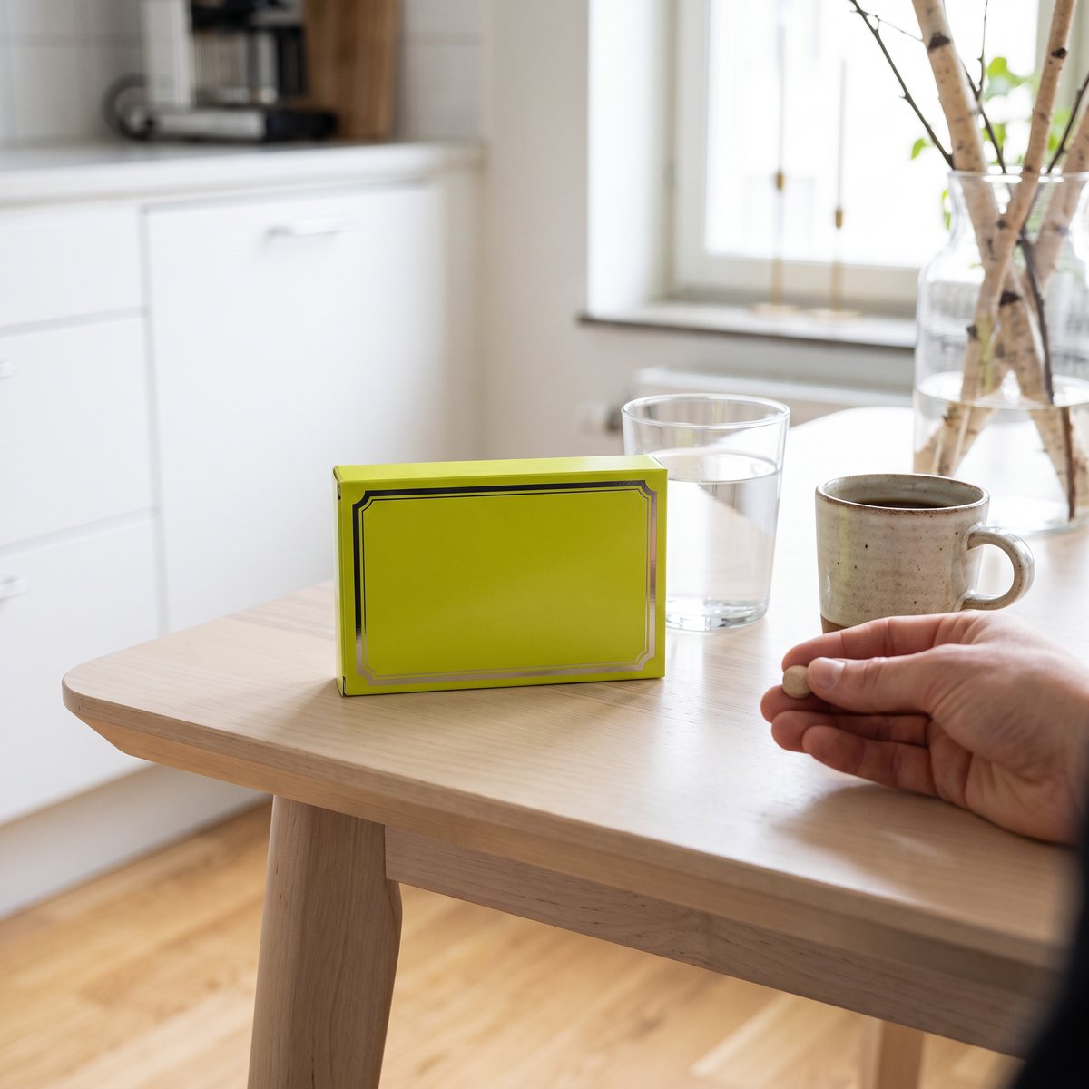 Pharma Nord Bio-Pycnogenol-förpackning på ett frukostbord i ett svenskt kök, med vattenglas och en tablett i handen