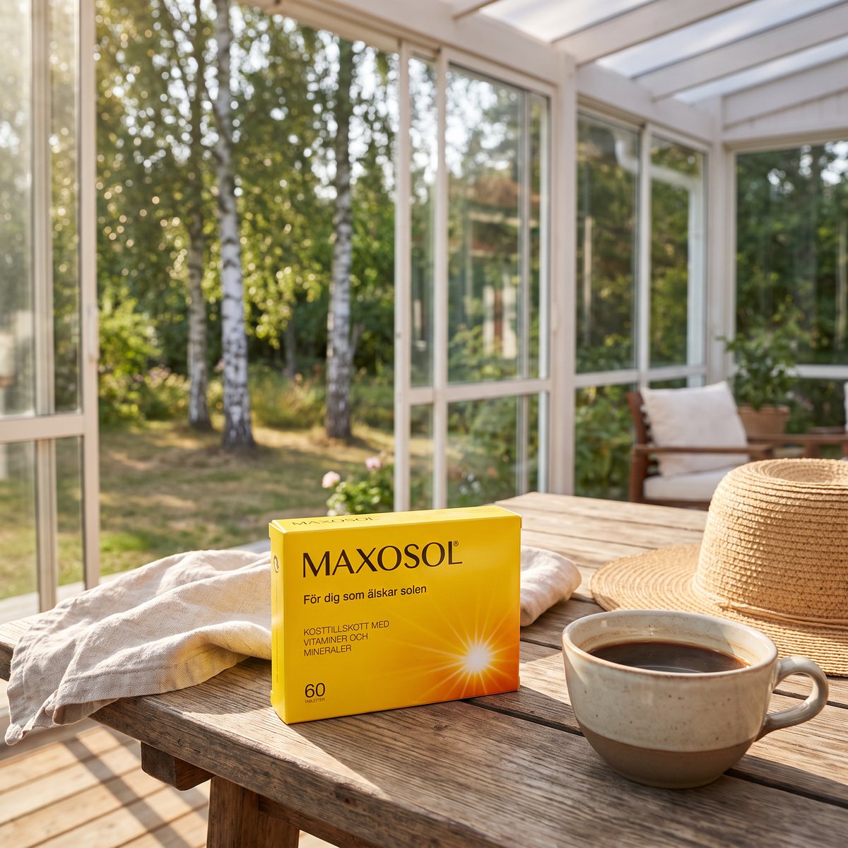 Maxosol-förpackning på ett träbord på en solig svensk glasveranda med kaffekopp och solhatt