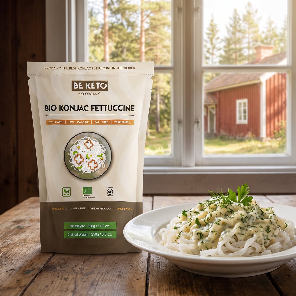 BeKeto Konjac Fettuccine i påse på ett rustikt träbord i ett svenskt sommarstugekök, bredvid en tallrik fettuccine